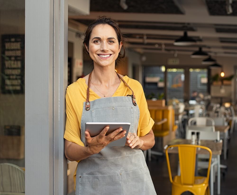 Small business owner in front of her cafe looking at camera