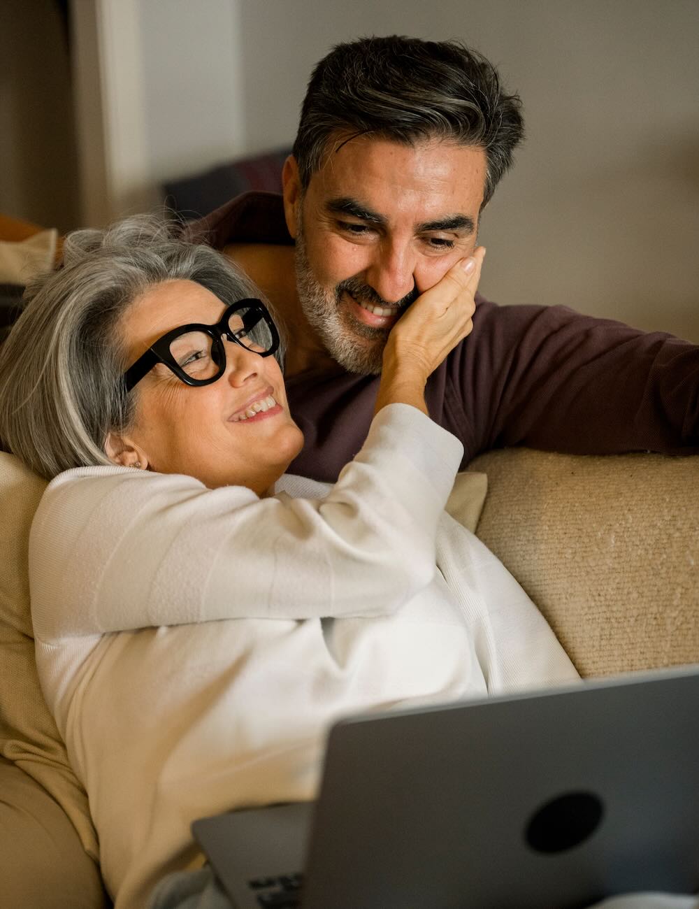 Mature couple smiling resting on a couch
