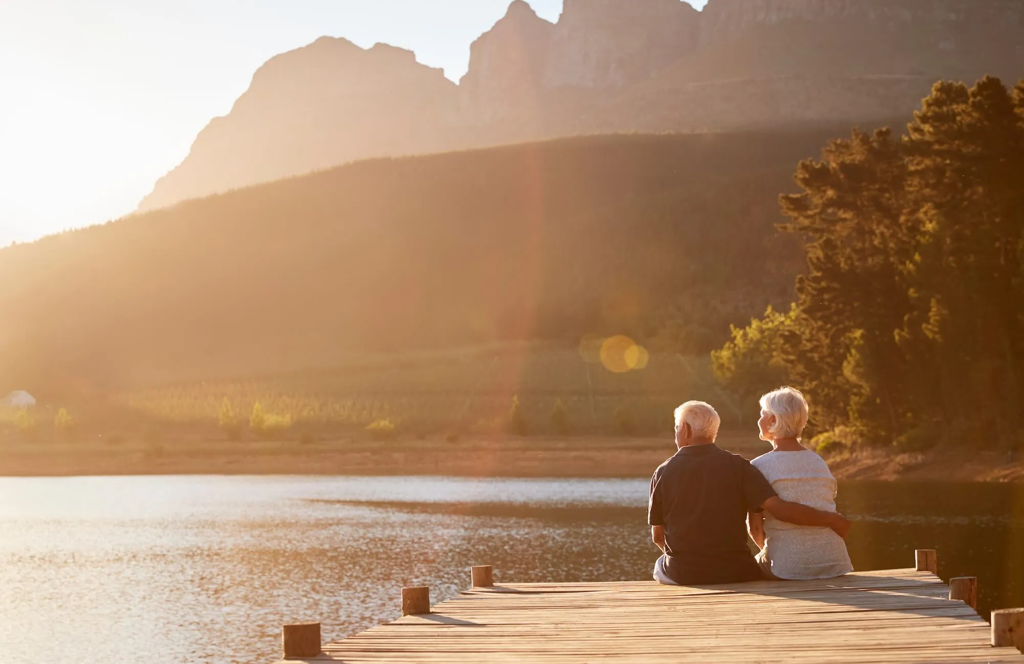 old couple watching sunset near the lake